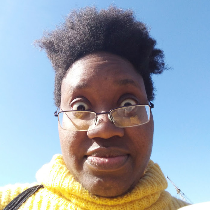 selfie of LiLi Kathleen, a look of surprise, blue skies and a yellow jumper