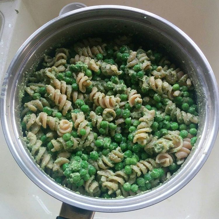 saucepan of fusilli pasta and petis pois peas coated in a light green pesto